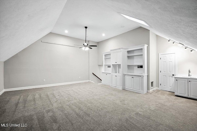 unfurnished living room featuring sink, vaulted ceiling, light carpet, and a textured ceiling