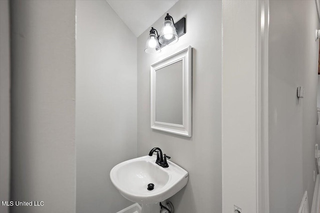 bathroom featuring lofted ceiling and sink