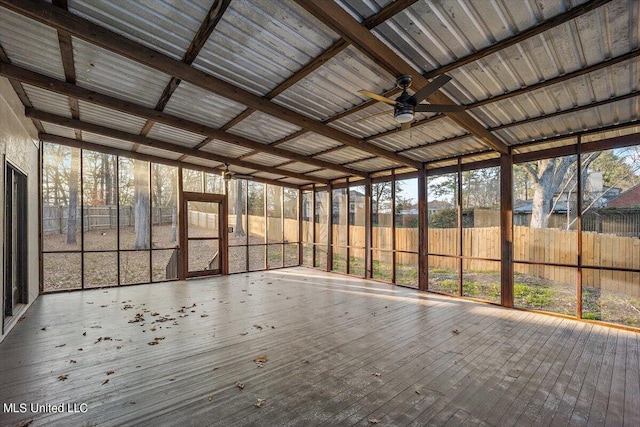 unfurnished sunroom featuring beamed ceiling, a healthy amount of sunlight, and ceiling fan