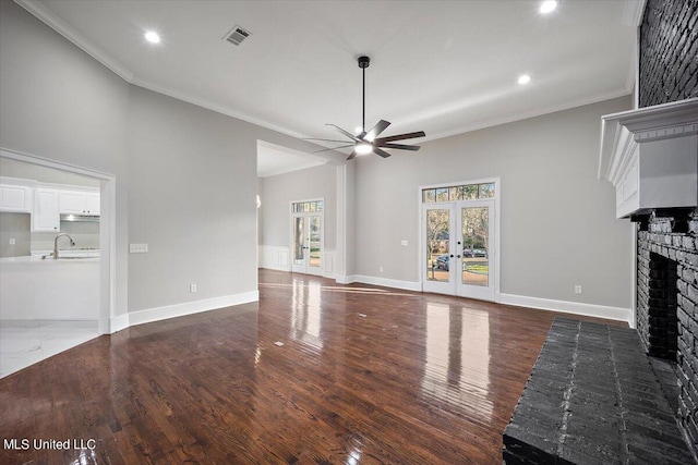 unfurnished living room with crown molding, dark hardwood / wood-style flooring, and a brick fireplace