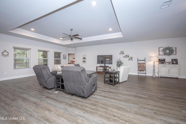 living room featuring hardwood / wood-style floors, ceiling fan, ornamental molding, and a tray ceiling