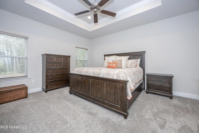 carpeted bedroom featuring ceiling fan, crown molding, and a tray ceiling