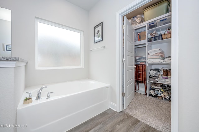 bathroom with wood-type flooring and a tub to relax in