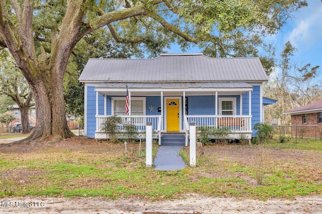 bungalow-style home with metal roof, fence, and a porch