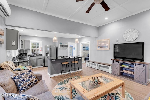 living area with light wood finished floors, baseboards, ceiling fan, an AC wall unit, and recessed lighting