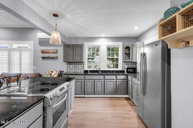 kitchen with appliances with stainless steel finishes, light wood-style flooring, gray cabinetry, and tasteful backsplash