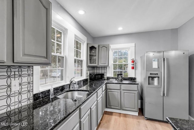 kitchen with stainless steel fridge, decorative backsplash, a sink, and gray cabinetry