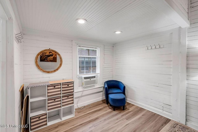 sitting room with light wood-style flooring, wood walls, cooling unit, wooden ceiling, and baseboards