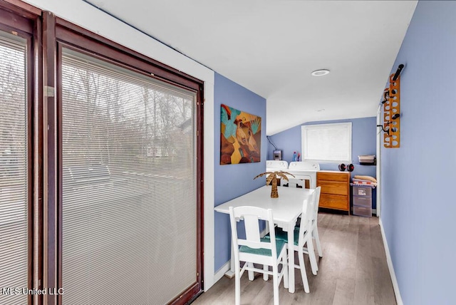 dining space featuring baseboards, vaulted ceiling, light wood finished floors, and washing machine and clothes dryer