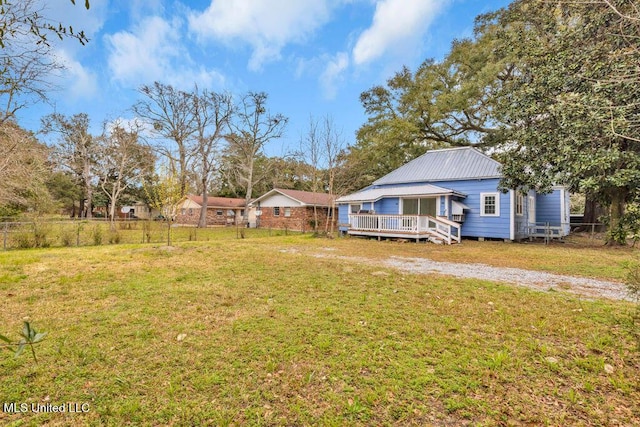 view of yard featuring fence, a deck, and dirt driveway