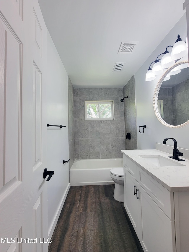 full bathroom with vanity, toilet, tiled shower / bath combo, and hardwood / wood-style floors