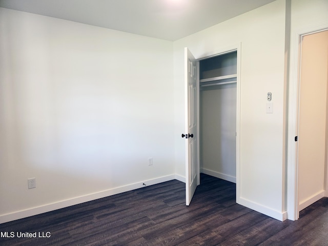 unfurnished bedroom featuring a closet and dark hardwood / wood-style flooring