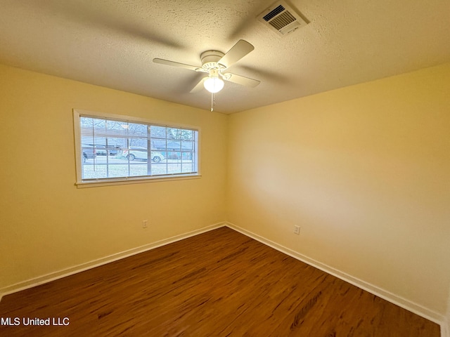 unfurnished room with ceiling fan, a textured ceiling, dark wood-style flooring, visible vents, and baseboards