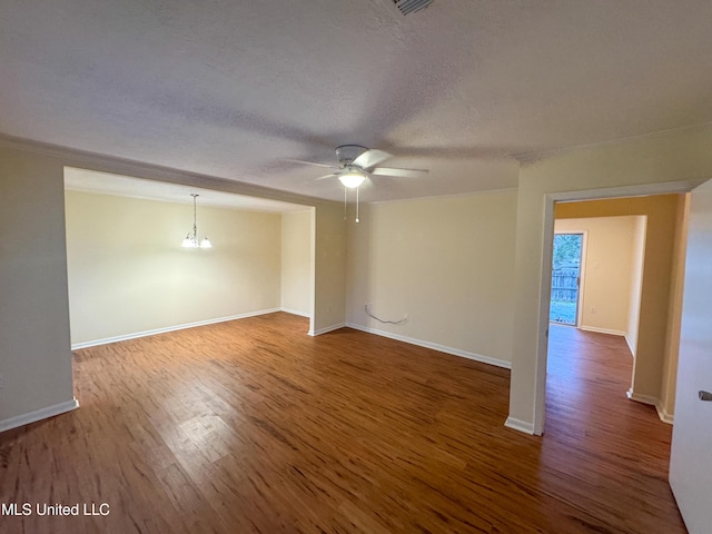 empty room with a textured ceiling, ceiling fan with notable chandelier, wood finished floors, and baseboards