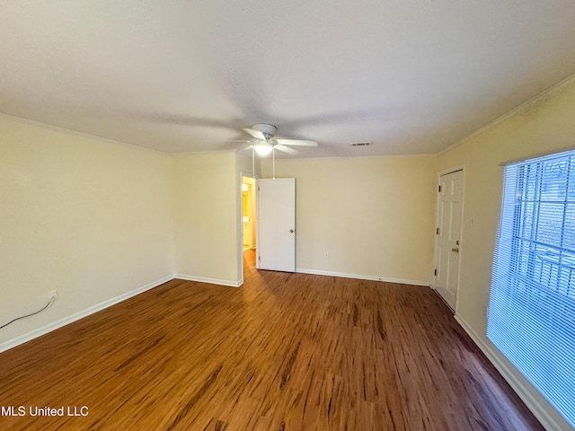 unfurnished room with wood finished floors, a ceiling fan, visible vents, baseboards, and ornamental molding