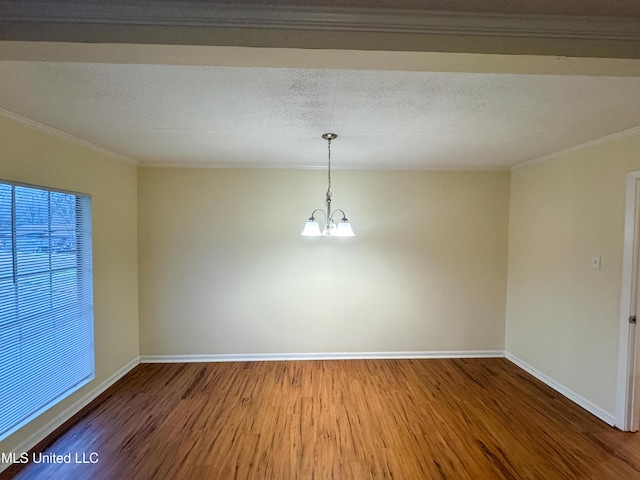 spare room featuring an inviting chandelier, crown molding, baseboards, and wood finished floors