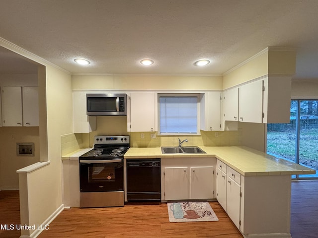 kitchen featuring a sink, white cabinets, appliances with stainless steel finishes, light wood finished floors, and crown molding