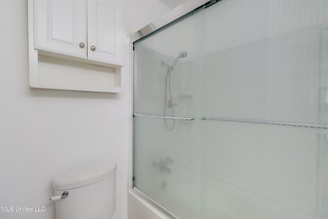bathroom featuring toilet and combined bath / shower with glass door