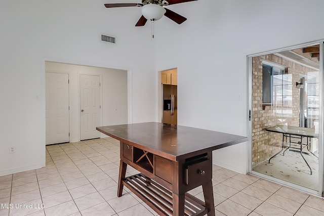 kitchen featuring stainless steel fridge with ice dispenser, light tile patterned floors, ceiling fan, and a high ceiling