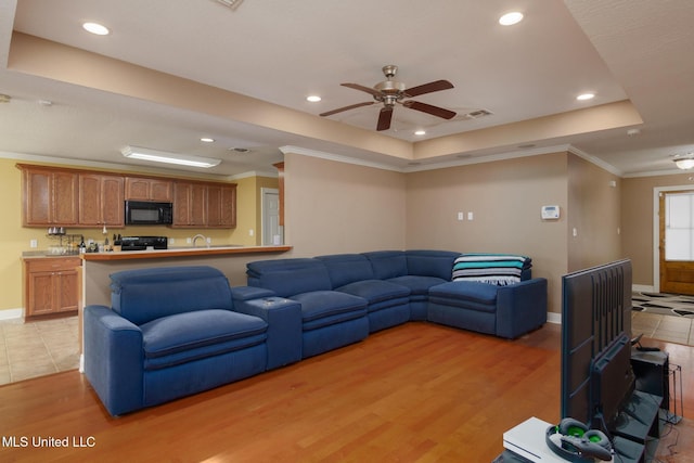 living room with crown molding, ceiling fan, a raised ceiling, and light hardwood / wood-style flooring