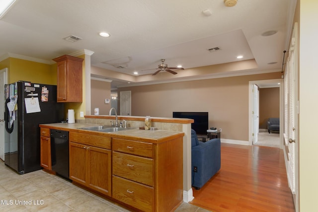 kitchen featuring sink, a tray ceiling, tile counters, black appliances, and ornamental molding