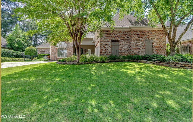 view of front of property with brick siding, a front yard, and a shingled roof