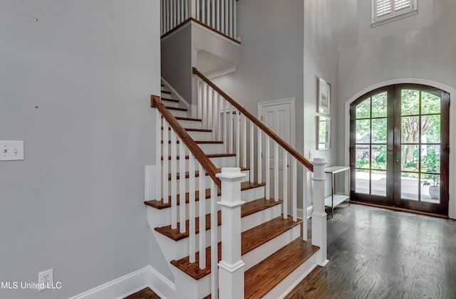 entryway with french doors, a towering ceiling, wood finished floors, stairway, and baseboards
