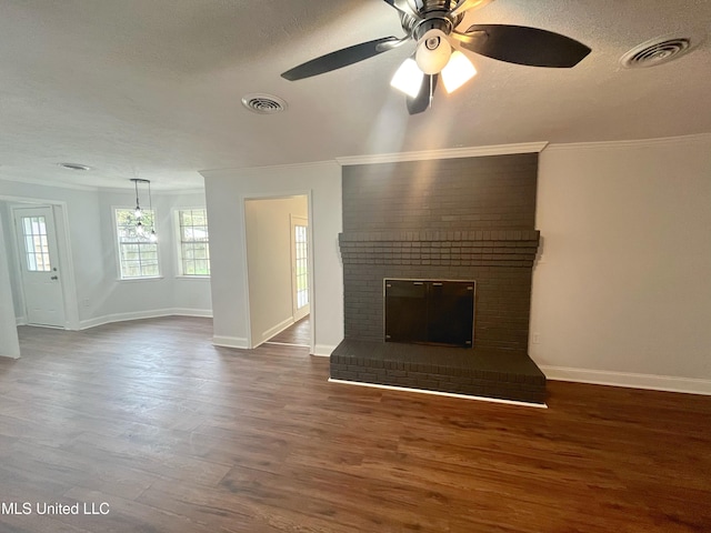 unfurnished living room featuring a brick fireplace, ceiling fan, ornamental molding, a textured ceiling, and dark hardwood / wood-style flooring