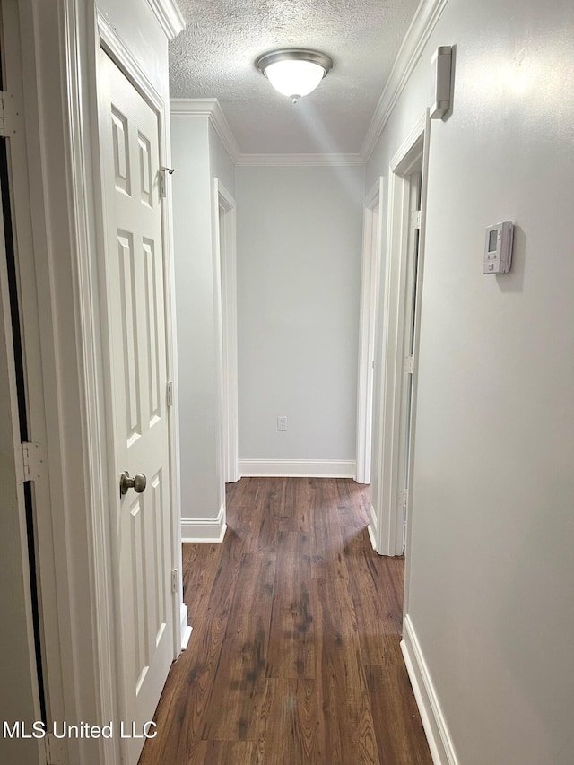 hallway with a textured ceiling, dark hardwood / wood-style floors, and ornamental molding