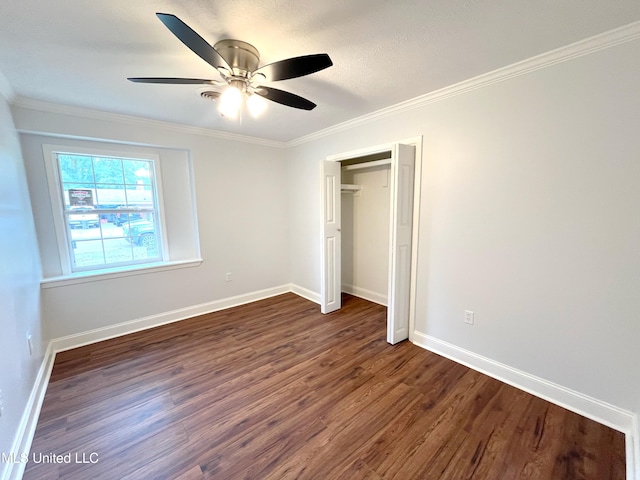 unfurnished bedroom featuring a textured ceiling, ceiling fan, crown molding, dark wood-type flooring, and a closet