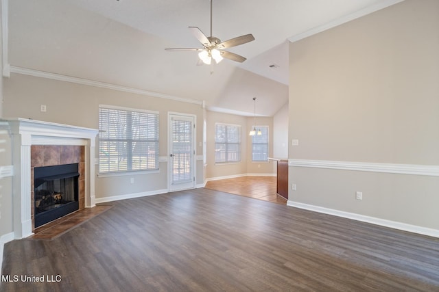 unfurnished living room featuring crown molding, a tile fireplace, ceiling fan, dark hardwood / wood-style floors, and lofted ceiling