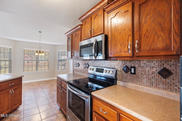 kitchen with a wealth of natural light, appliances with stainless steel finishes, tasteful backsplash, and light tile patterned flooring