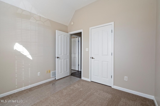 unfurnished bedroom with light colored carpet and vaulted ceiling