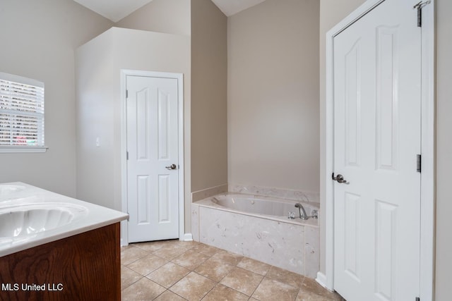 bathroom with a relaxing tiled tub, vanity, and tile patterned flooring