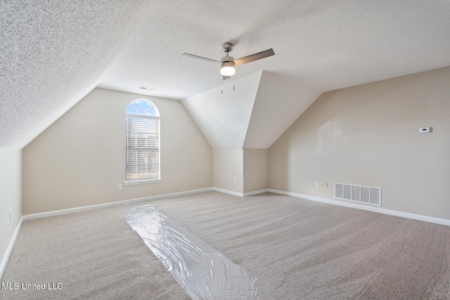 additional living space with ceiling fan, a textured ceiling, lofted ceiling, and light carpet