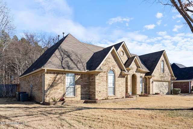 view of front facade with central AC, a garage, and a front lawn