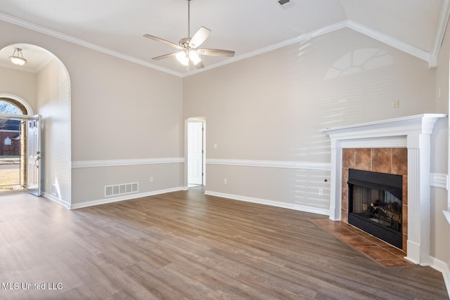 unfurnished living room featuring crown molding, wood-type flooring, ceiling fan, a wealth of natural light, and a tile fireplace