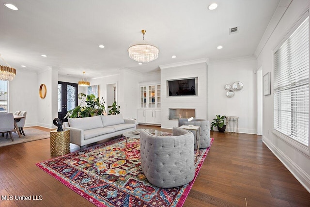 living room with a large fireplace, a healthy amount of sunlight, and dark hardwood / wood-style flooring