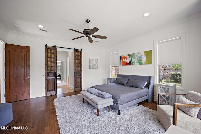 bedroom featuring crown molding, dark hardwood / wood-style floors, a barn door, and ceiling fan