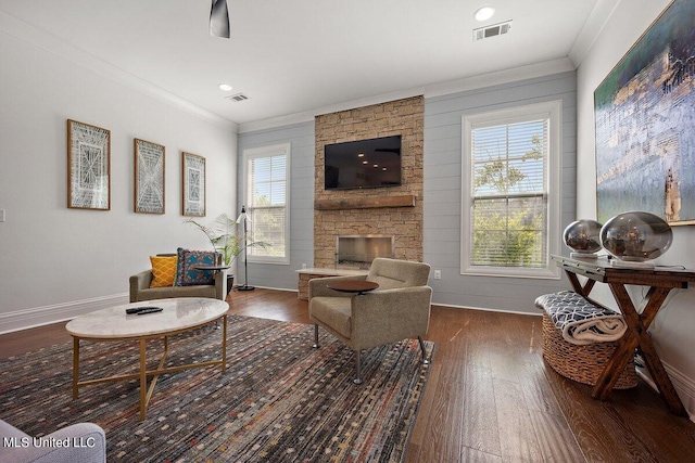 living room featuring a fireplace, crown molding, plenty of natural light, and dark hardwood / wood-style flooring