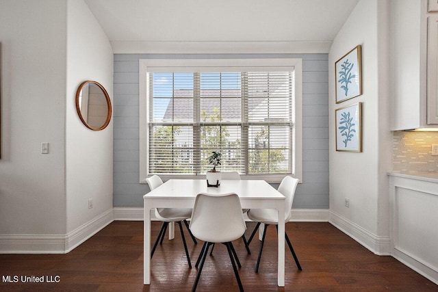 dining room with vaulted ceiling, dark hardwood / wood-style flooring, and wooden walls