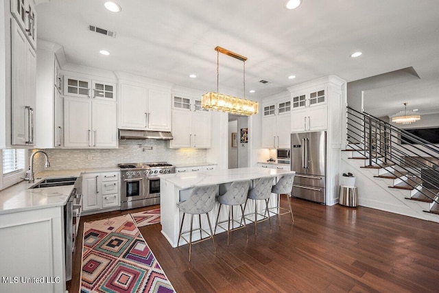 kitchen with high end appliances, a center island, white cabinetry, and dark wood-type flooring