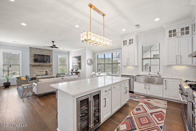 kitchen with appliances with stainless steel finishes, white cabinetry, sink, pendant lighting, and a center island