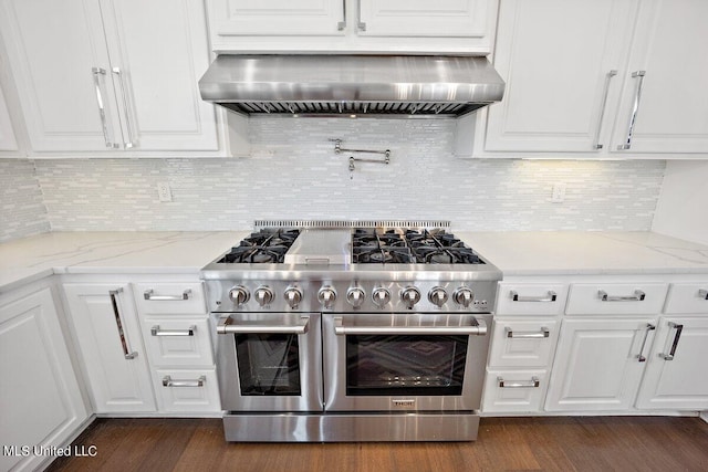 kitchen featuring light stone countertops, range with two ovens, dark hardwood / wood-style flooring, wall chimney exhaust hood, and white cabinets