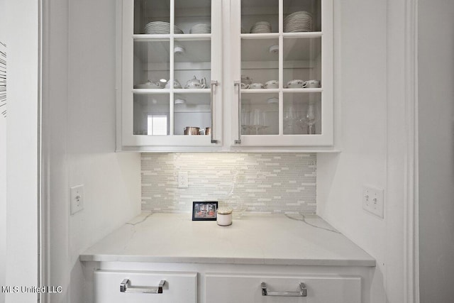 bar featuring white cabinetry, tasteful backsplash, and light stone counters