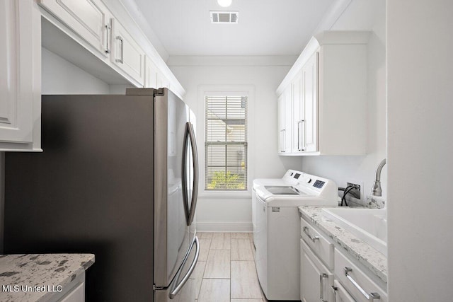 laundry room featuring ornamental molding, separate washer and dryer, and cabinets