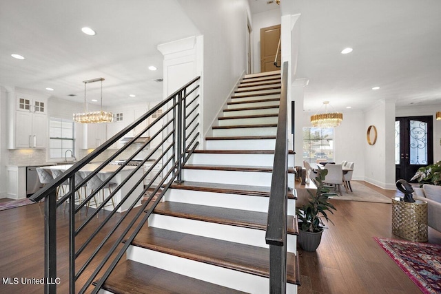 stairway with hardwood / wood-style flooring, sink, and a chandelier