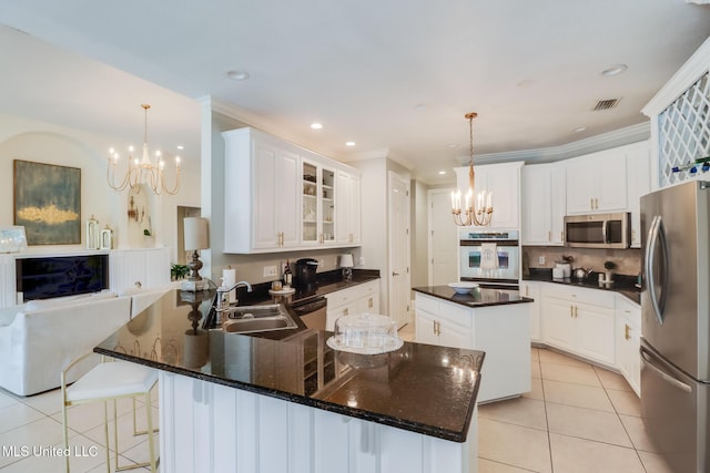 kitchen with hanging light fixtures, appliances with stainless steel finishes, an inviting chandelier, and kitchen peninsula