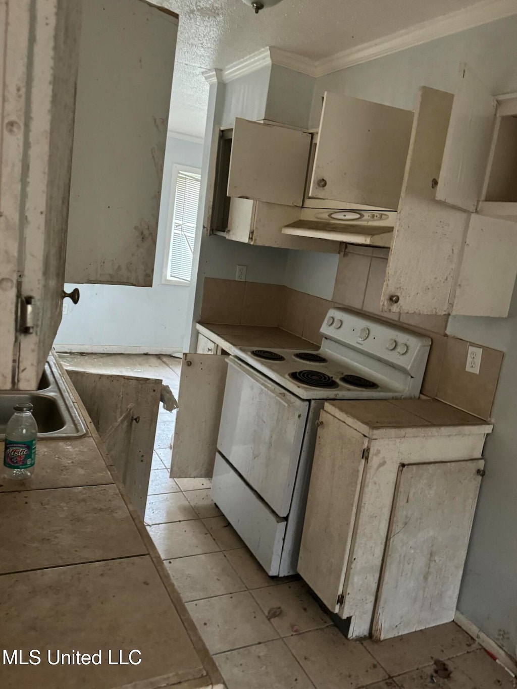 kitchen with extractor fan, cream cabinets, ornamental molding, light tile patterned floors, and electric stove