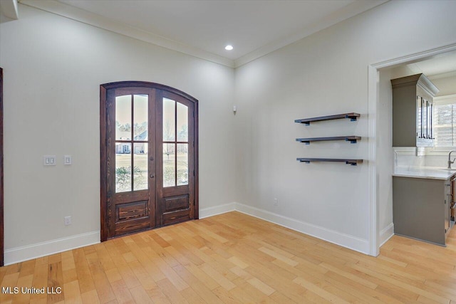 foyer featuring french doors, light hardwood / wood-style floors, and crown molding